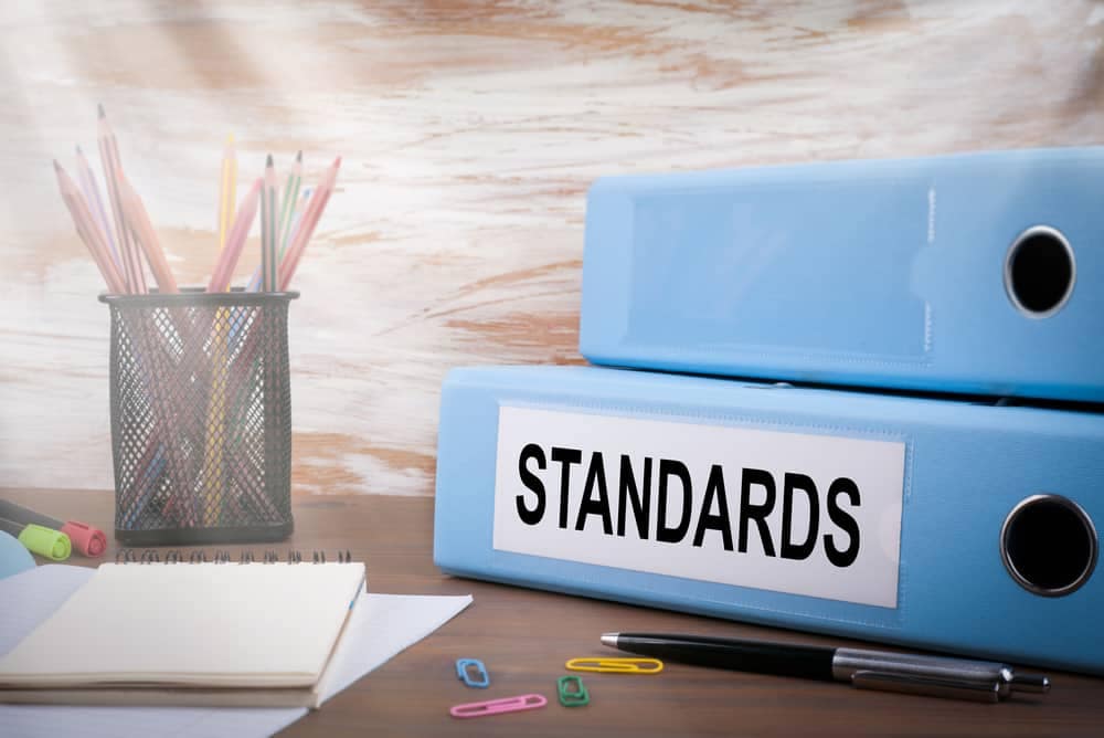 A blue binder with the word standards on it, labeled RVIA, sits on top of a desk.