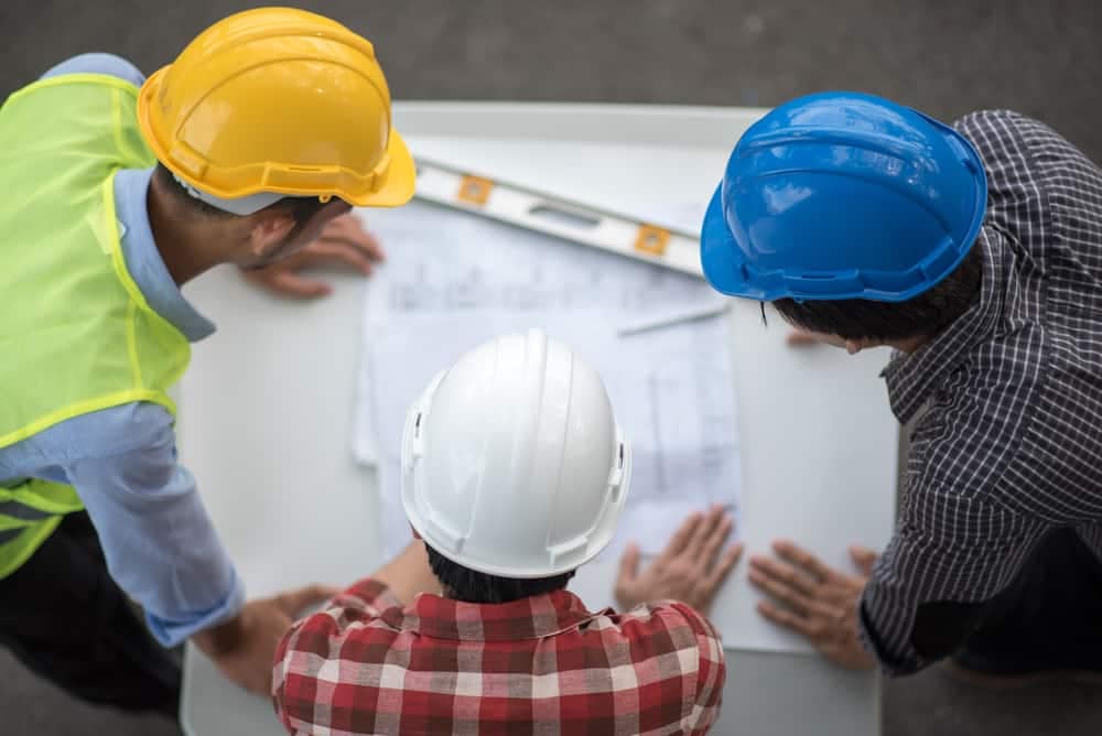 Three construction workers with hard hats looking at plans for the Snake River Gateways Project.