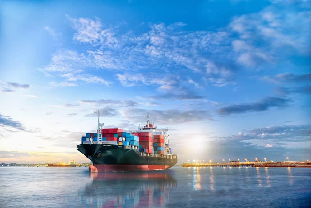 A large container ship is docked in a body of water, showcasing the impact of Ocean Shipping Reform.