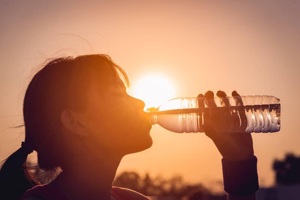 An advocate drinking purified water from a bottle at sunset.