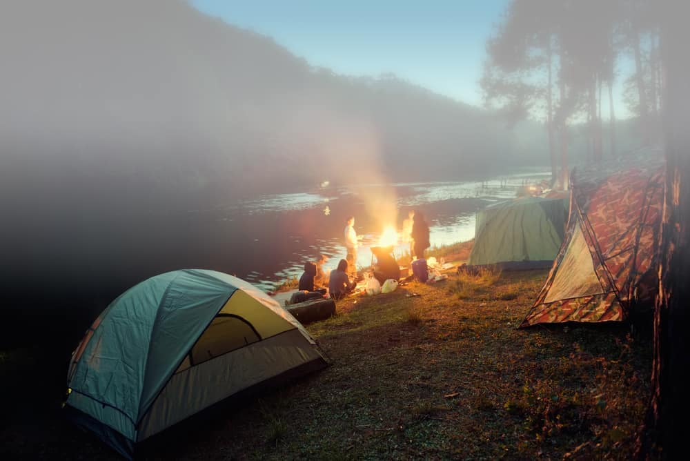 A group of tents by a river with a campfire at Parks Canada.