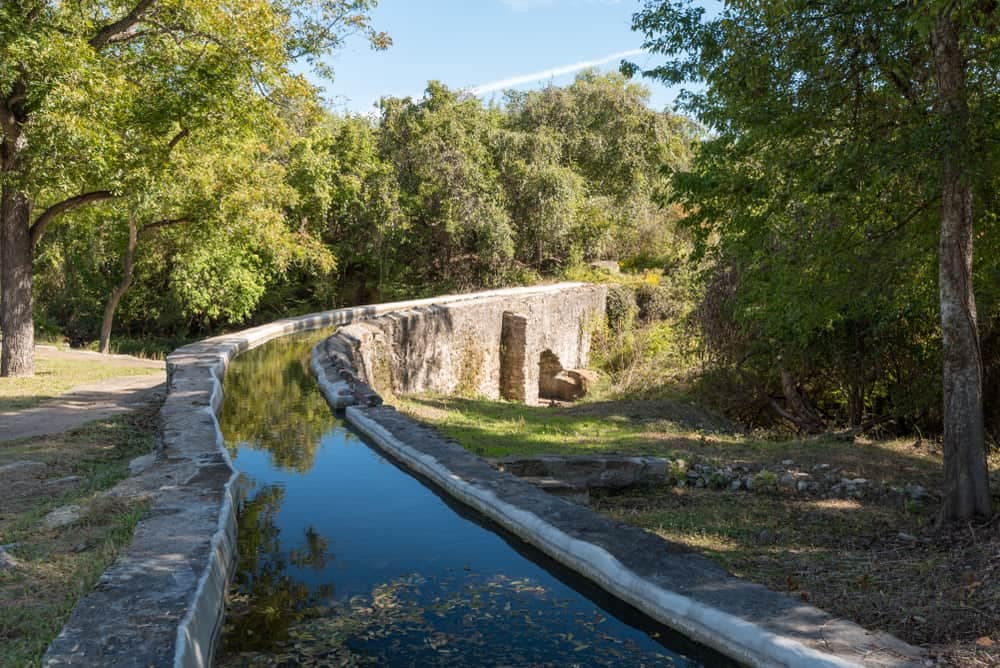 A waterway in the middle of a park undergoing repairs with trees.