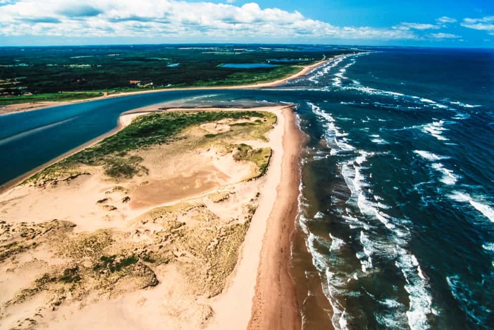 Enjoy a stunning aerial view of PEI National Park, with its sandy beach meeting the endless expanse of the ocean.