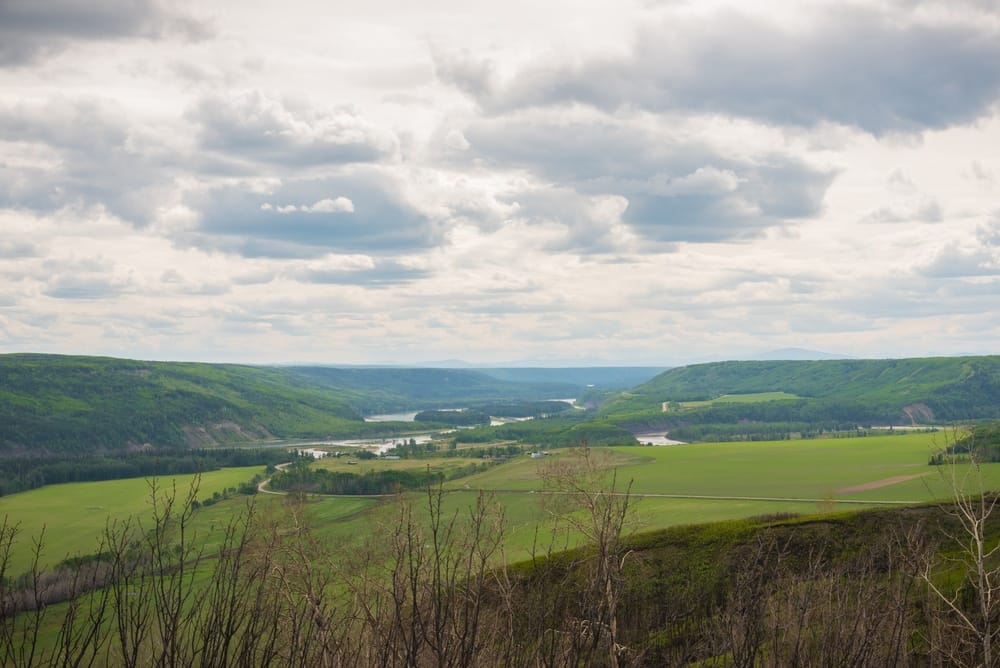 Let's Camp at Blackfoot Regional Park, a green valley nestled with majestic mountains in the background.