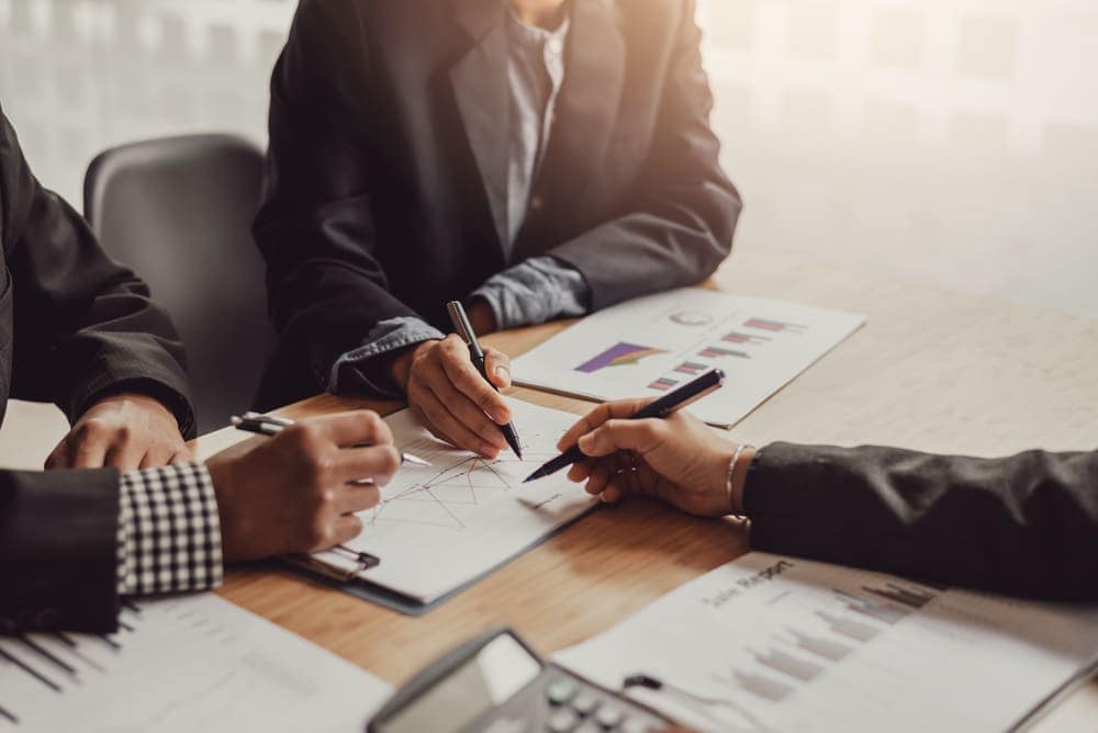The Dyrt introduces their new head of sales as a group of business people working together at a table.