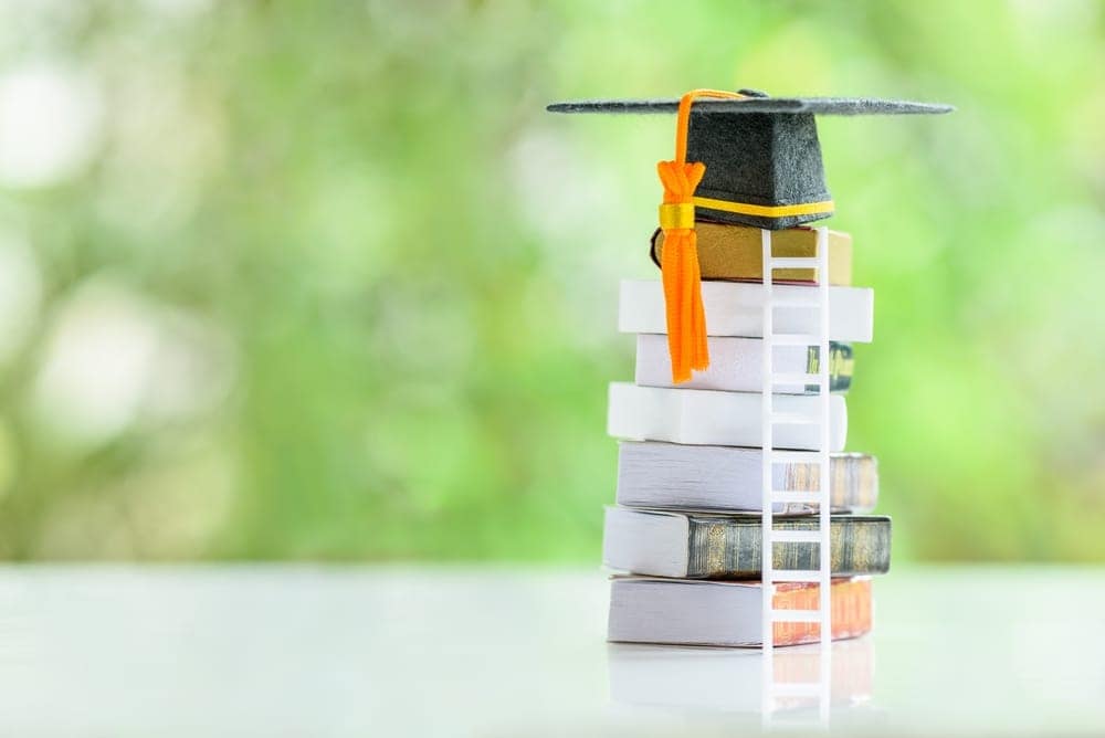 A stack of books with a graduation cap on top, representing the Mason Upperman College Scholarship program.