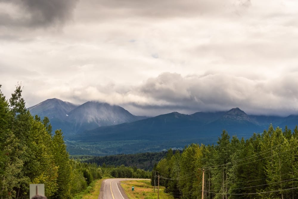 A road with trees and mountains in the background, perfect for tourism enthusiasts visiting Prince George's scenic landscapes.