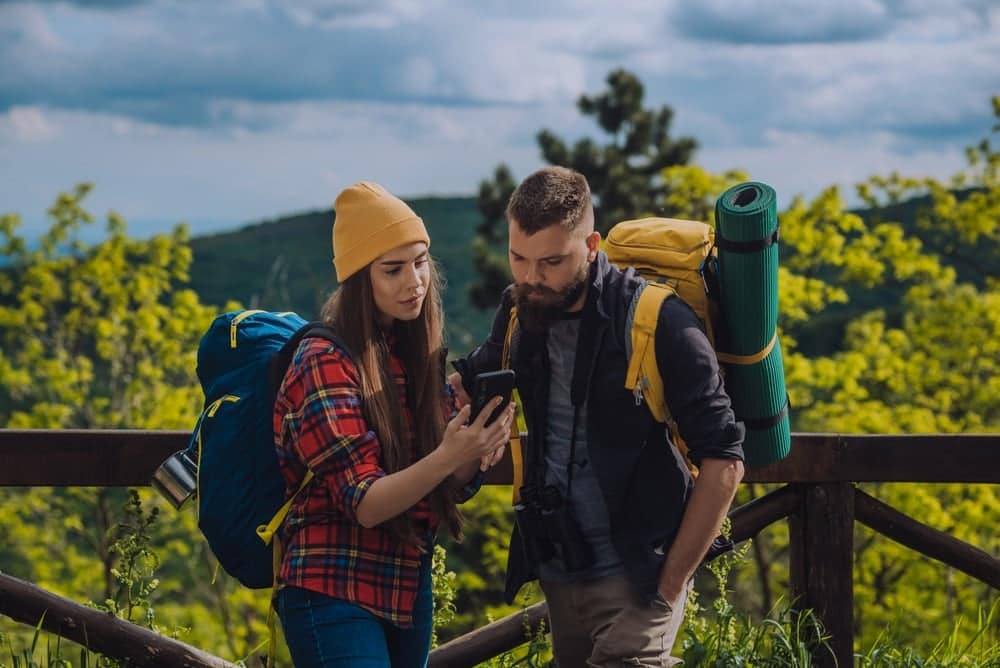 A couple enjoying a Digital Guest Experience while hiking in the mountains with Map Integration.