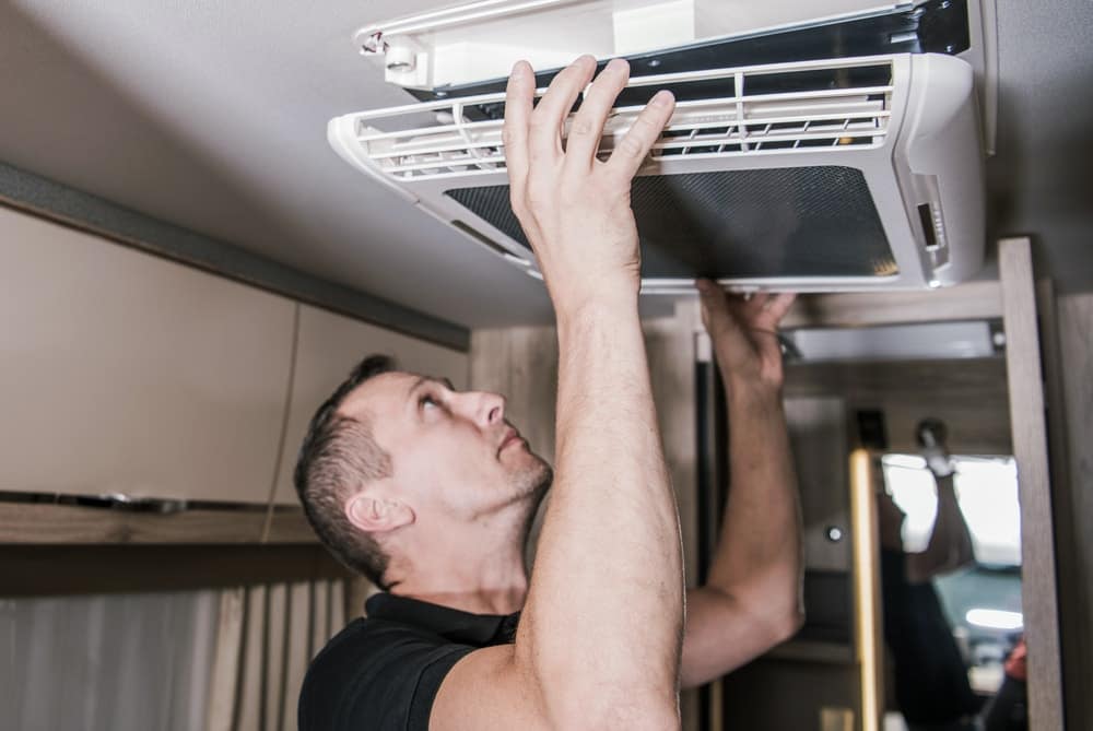 A man fixing an air conditioner in a recreational vehicle (RV) at the Florida RV Show.