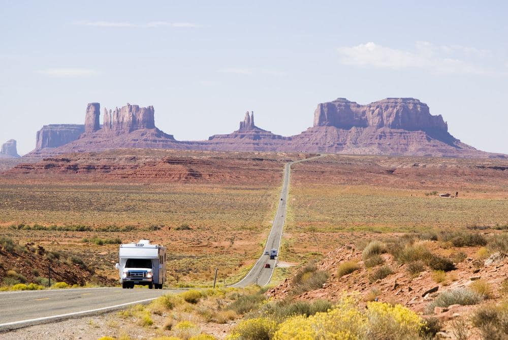 A truck is driving down a road in monument valley, arizona, showcasing the stunning outdoor scenery of the region.