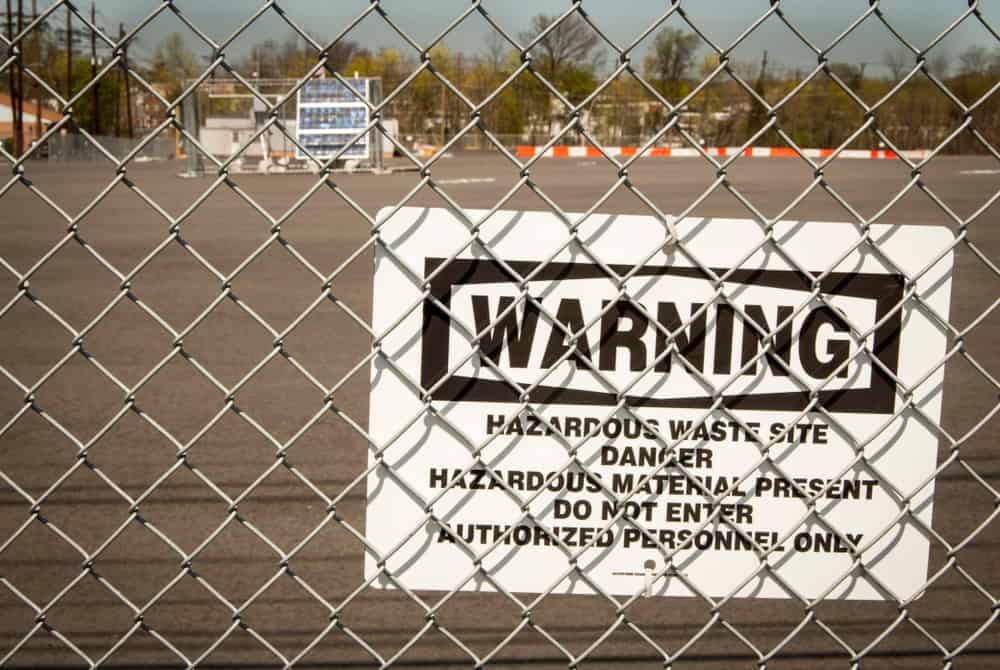A warning sign at a Superfund Site on a chain link fence.