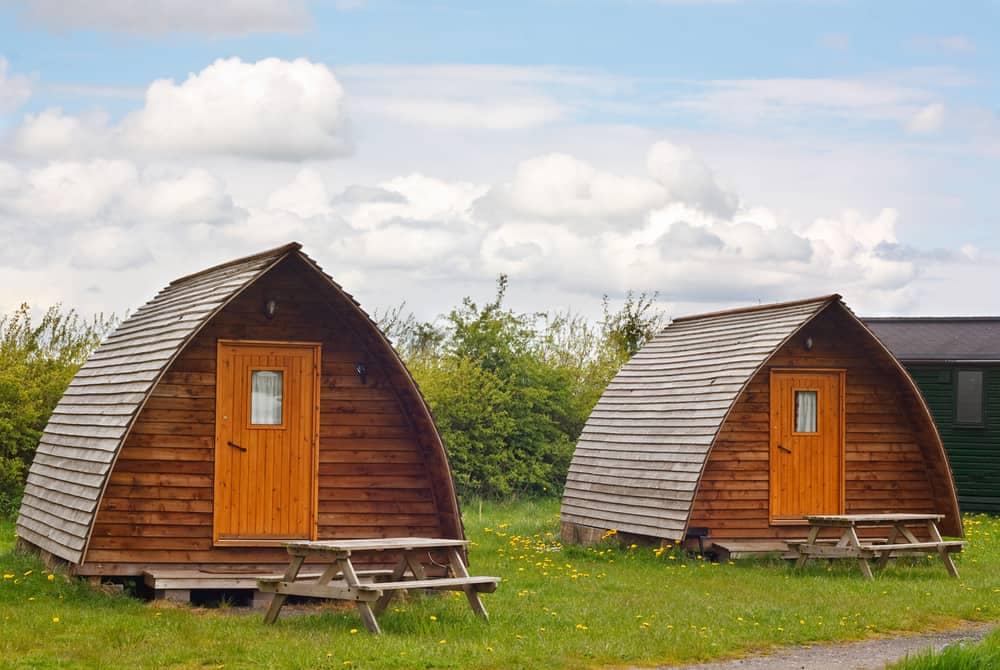 Two glamping cabins sitting next to each other in a field.