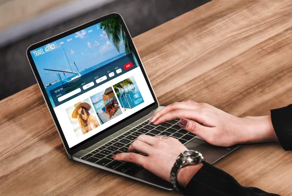 A person browsing a travel website on their laptop, researching camping options.