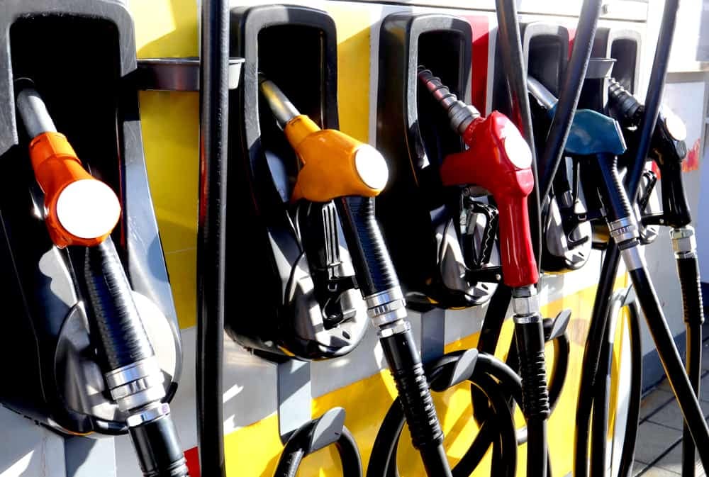 A line of gas pumps with different colored nozzles, offering varying fuel prices during the U.S. gas price crisis.