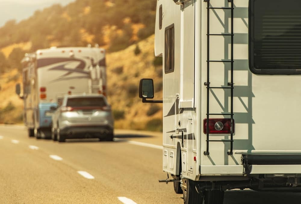 A Lazydays RV is driving down the road with a car behind it while traveling from Ohio to Arizona.