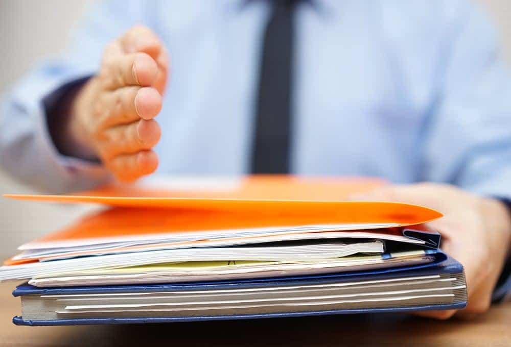 A man is holding a controversial folder full of RV Park review papers.