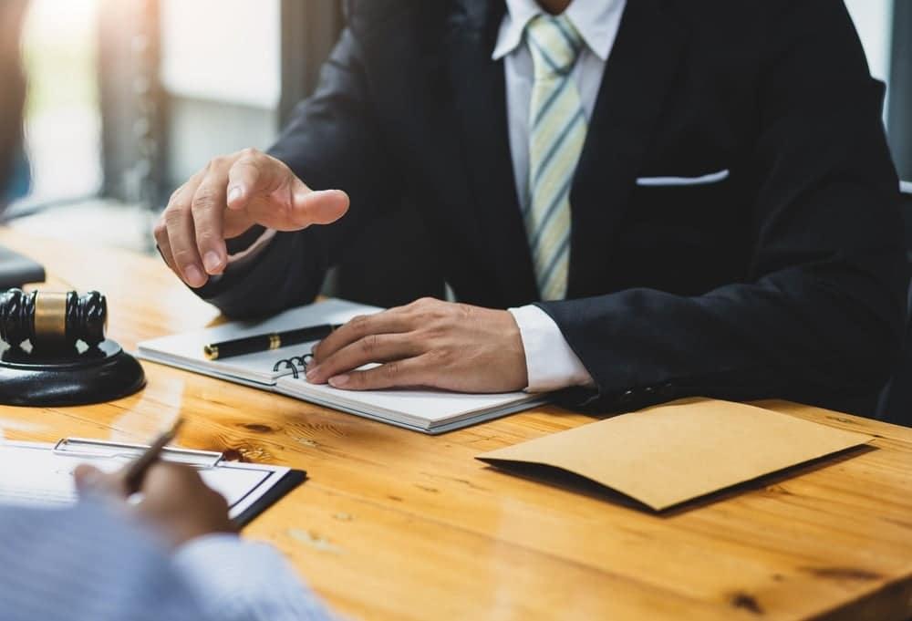 A businessman is talking to a lawyer about Welsh Government regulations at a desk.