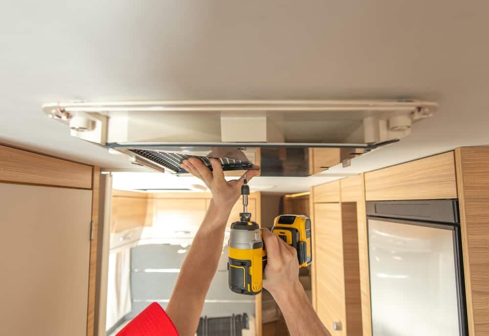 A Mobile RV Repair Service expertly uses a drill to install a light in a RV, ensuring top-notch service at Pull Through Sites.