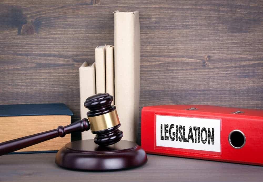 A judge gavel sits on top of a red folder and books on a wooden table in California.