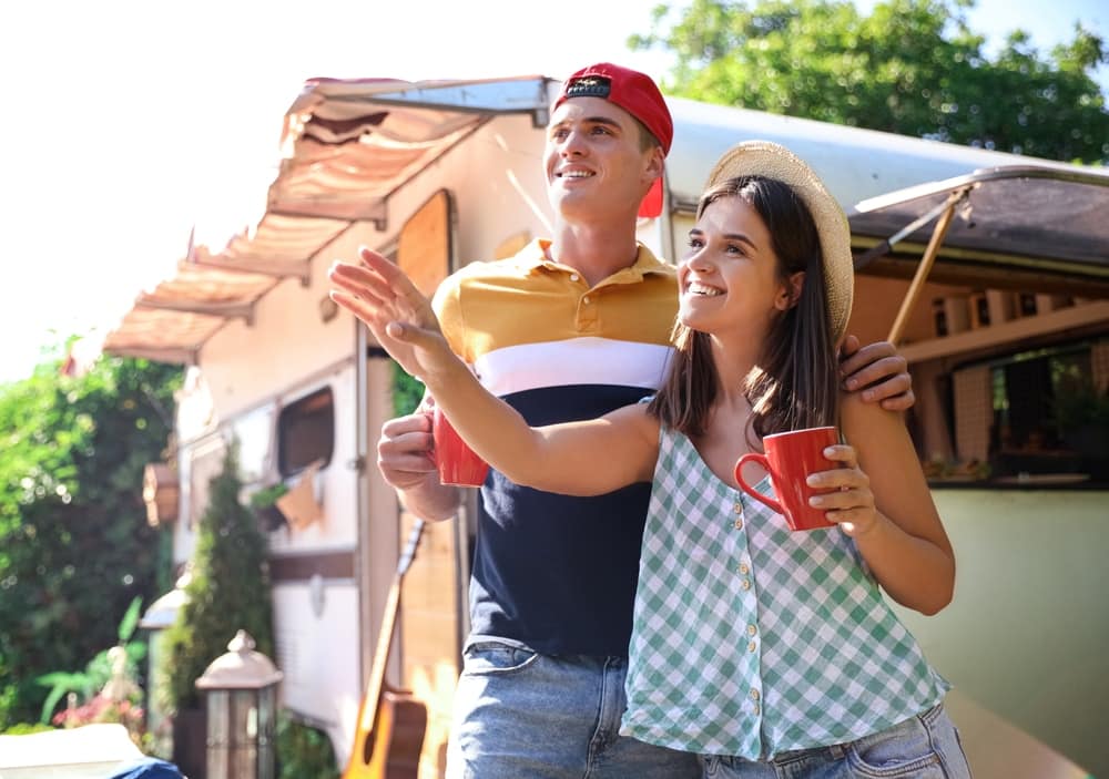 A couple standing outside of a Sun Communities camper trailer.