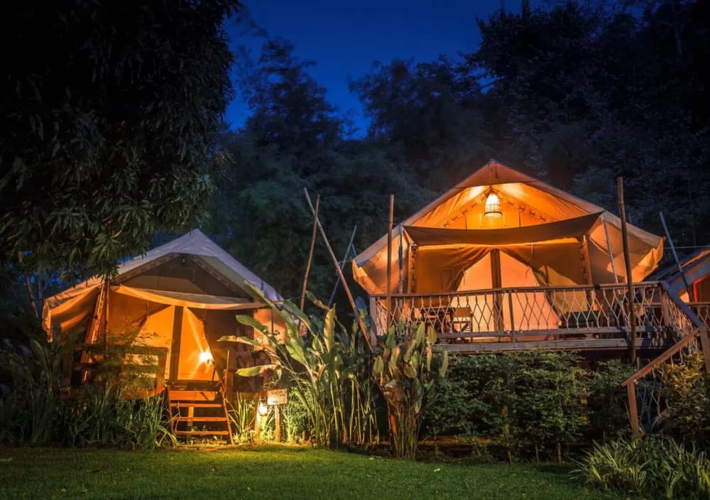 Two tents illuminated at night in a grassy area, at Hintok River Camp.