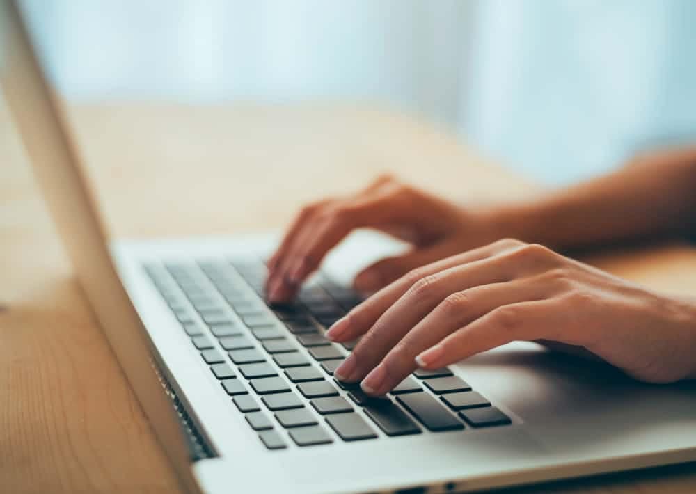 A woman using an AI chatbot on her laptop keyboard for unmatched convenience and instant answers.