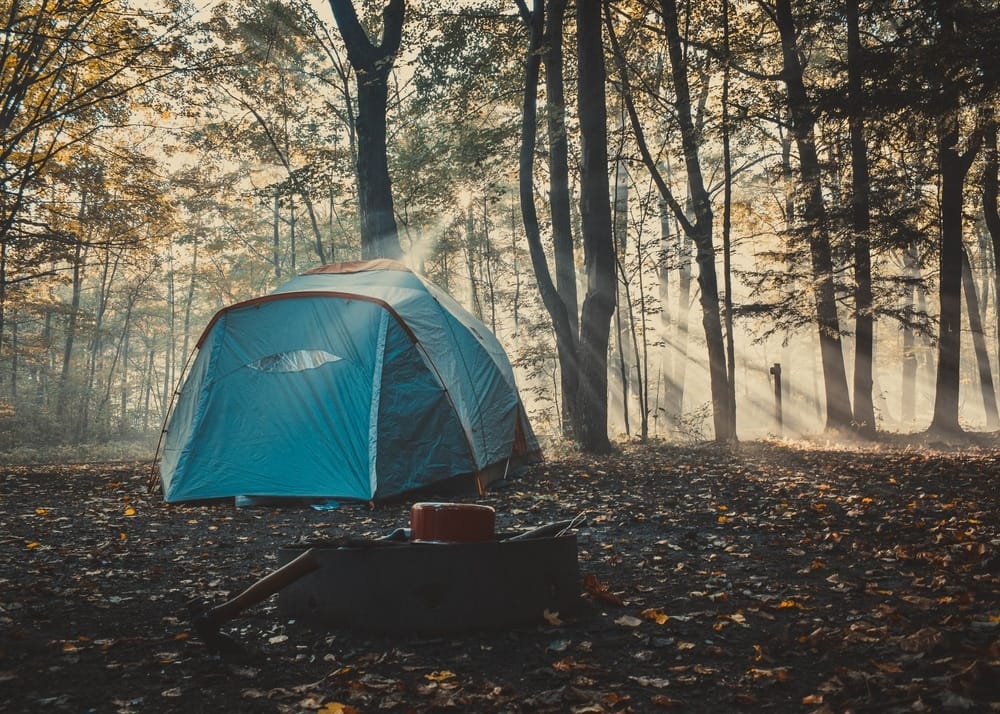 A camping tent is set up in the woods.