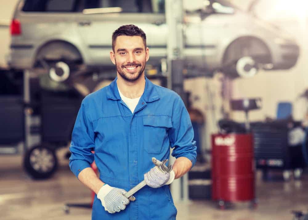 A mechanic at an American School Counselor Association Conference, holding a wrench in a garage.