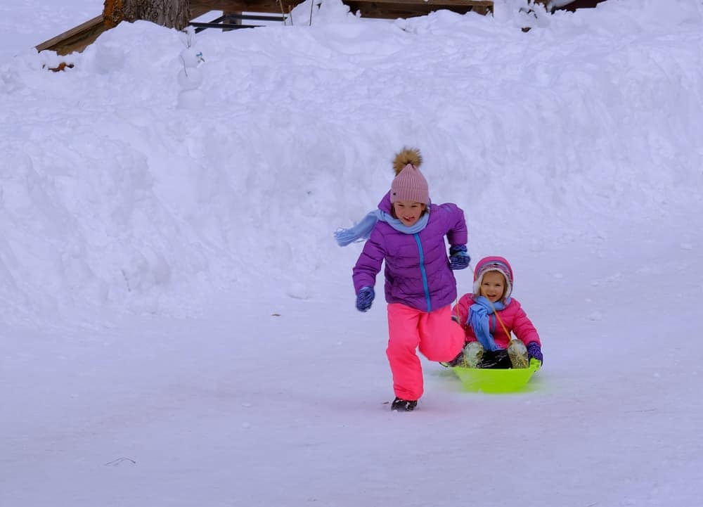 Two children sledding down a snowy hill in South Lake Tahoe, enjoying a family-friendly winter activity.