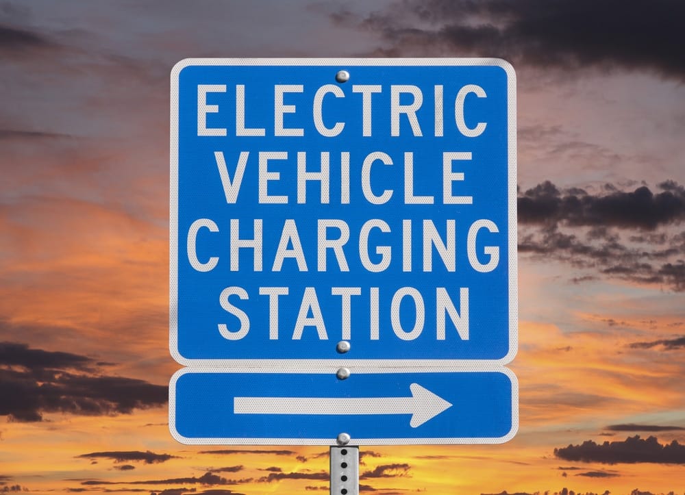 An EV Charging Stations sign in front of a sunset at Belle Isle.
