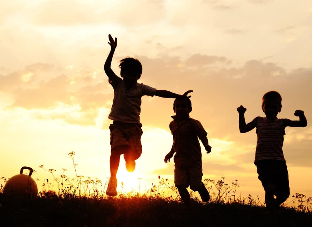 Children with Cancer playing in a field at sunset.