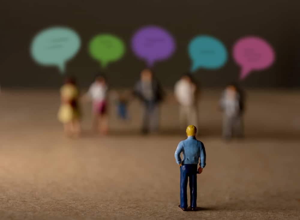 A man is standing in front of a group of people at the Hinsdale RV Park, with speech bubbles representing the opposition to a proposed idea.