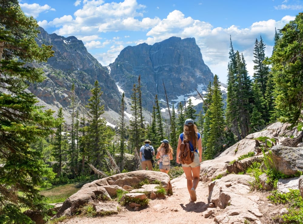A group of hikers from the Outdoor Recreation Industry Office hiking on a rocky trail in the mountains of Colorado.