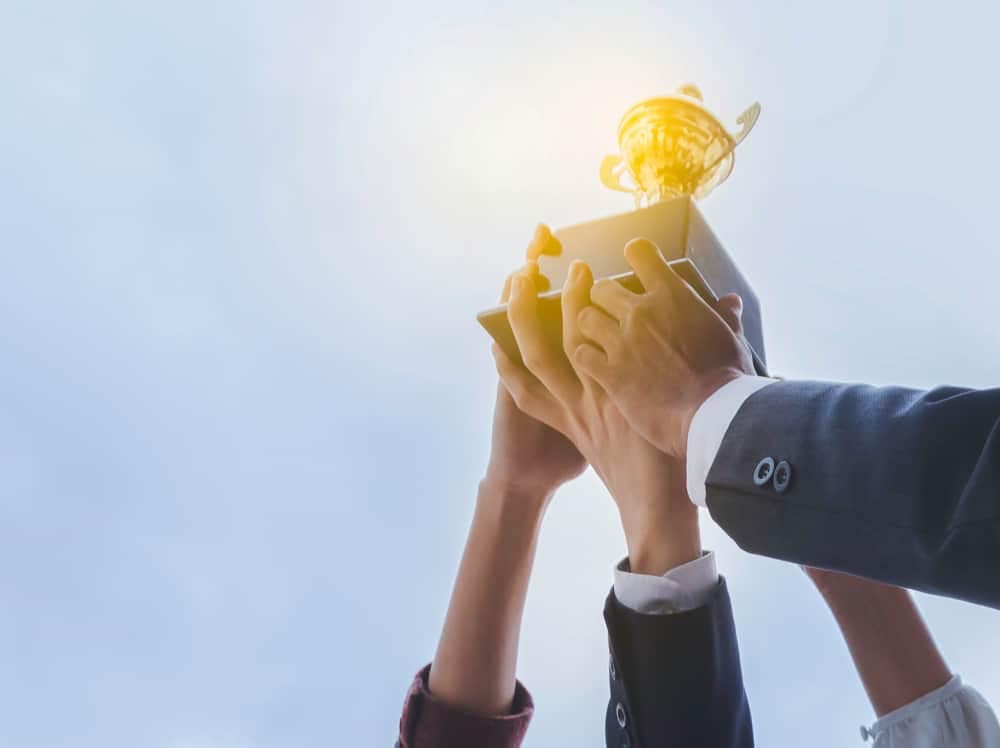 A group of business people holding up a trophy as a result of their outstanding performance in the RVDA Dealer Satisfaction Index Survey, representing their success in collaborating with top RV Manufacturers/Brands.