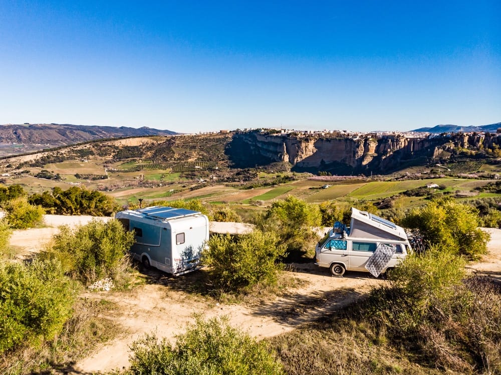 Two rvs parked on the side of a dirt road with X2Power Lithium Batteries.