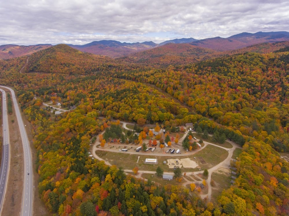 An aerial view of a mountain road surrounded by vibrant fall foliage in New Hampshire.