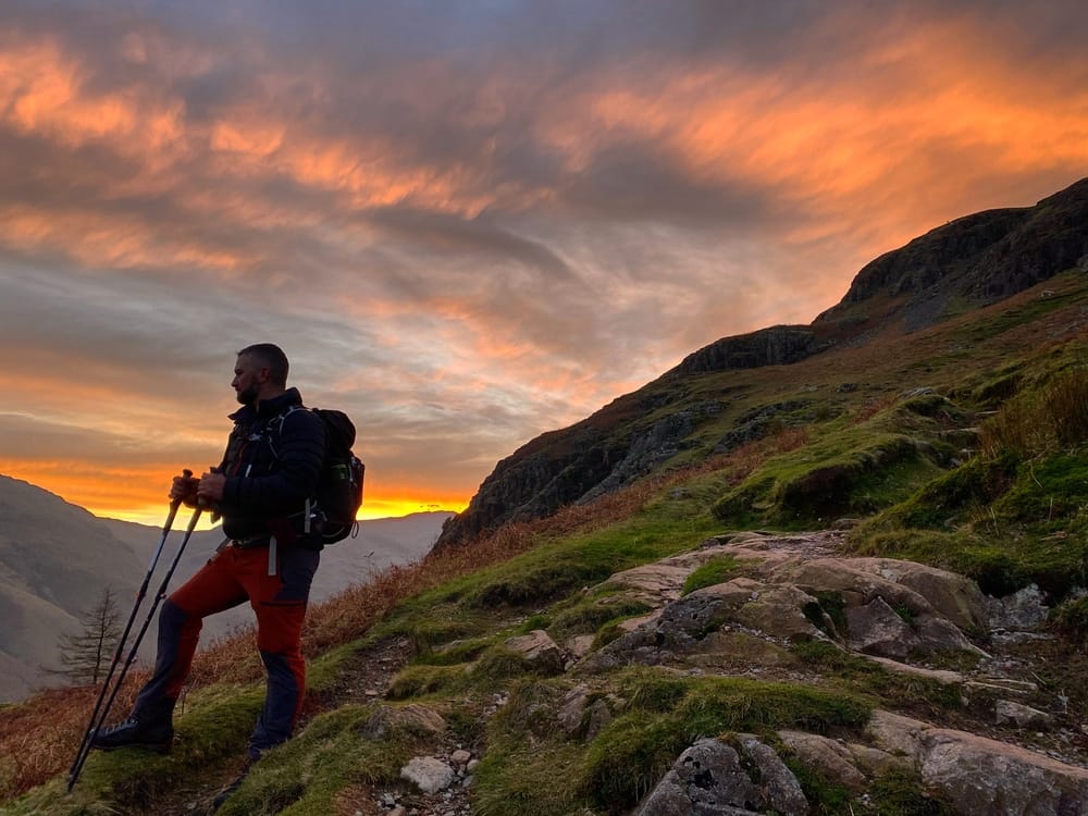 A hiker standing on a rocky trail at sunset, feeling a sense of serenity and solitude.