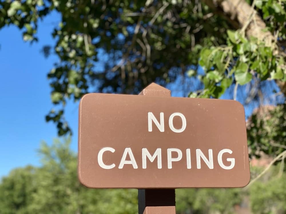 A no camping sign in front of a tree in Maggie Valley, surrounded by campgrounds.