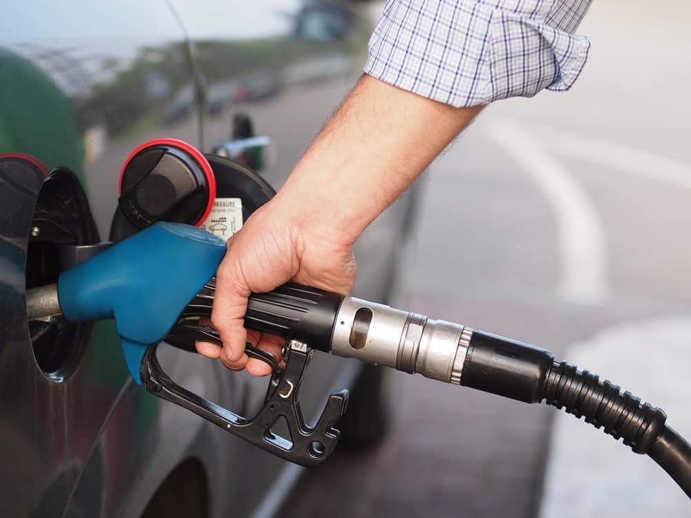 A person filling up a car with gas, concerned about the price of gasoline.