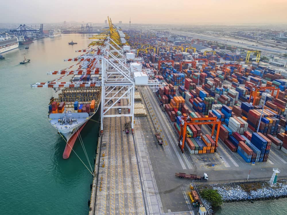 An aerial view of a container ship docked at a port, highlighting the impacts of Section 232 tariffs.