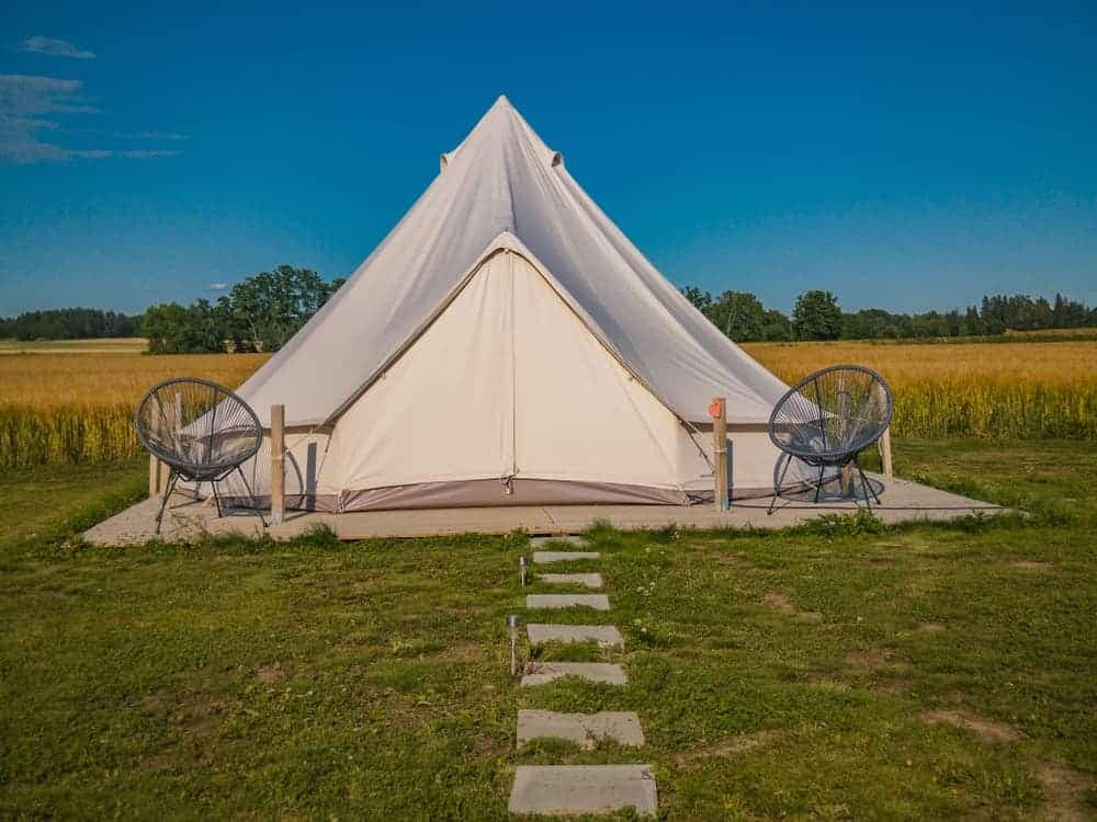 A white tent offering camping stays in the middle of a field.