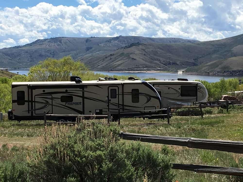 An rv parked in a grassy area near a lake, recommended by Tripadvisor Travelers' Choice Award.
