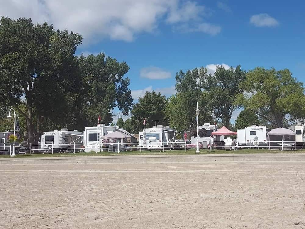 Rv park on a sandy beach with trees in the background, offering Campground Reservations.