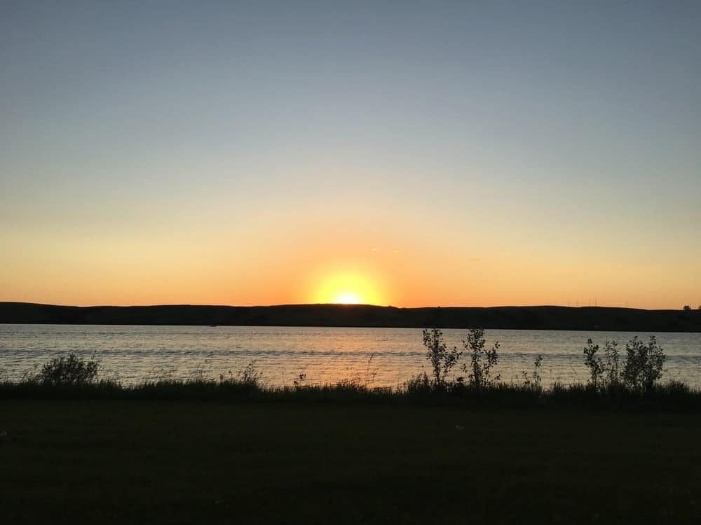 Explore the Great Outdoors during Saskatchewan Parks Week as the sun sets over a body of water.