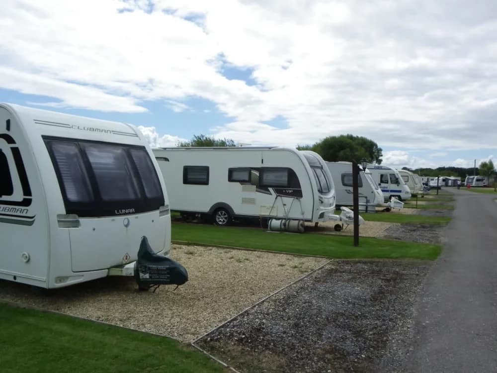A row of rvs parked in a grassy area, catering to Hinkley Point workers.