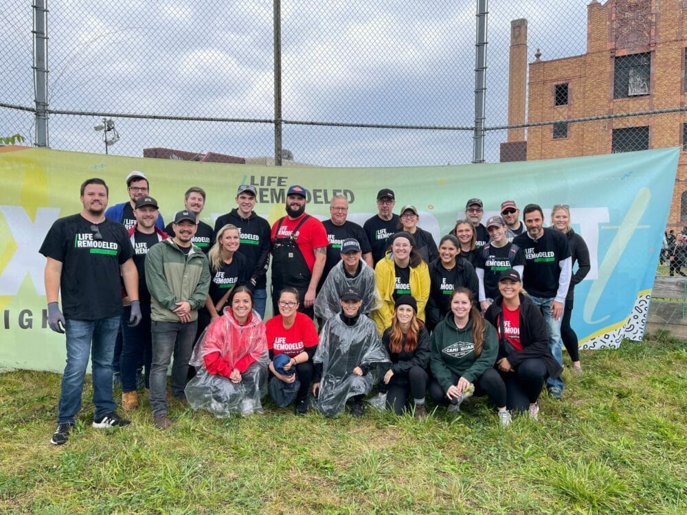 A group of people from Life Remodeled posing in front of a banner for Community Revitalization.
