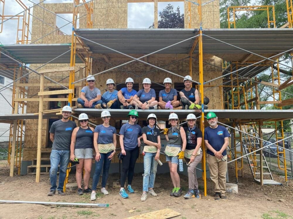 A group of people posing in front of a building under construction, showcasing its high design features.