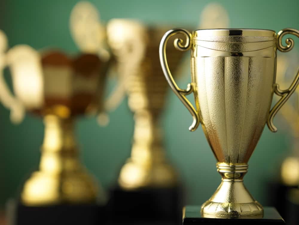 A collection of gold trophy trophies, meeting the criteria for excellence, placed on a table.