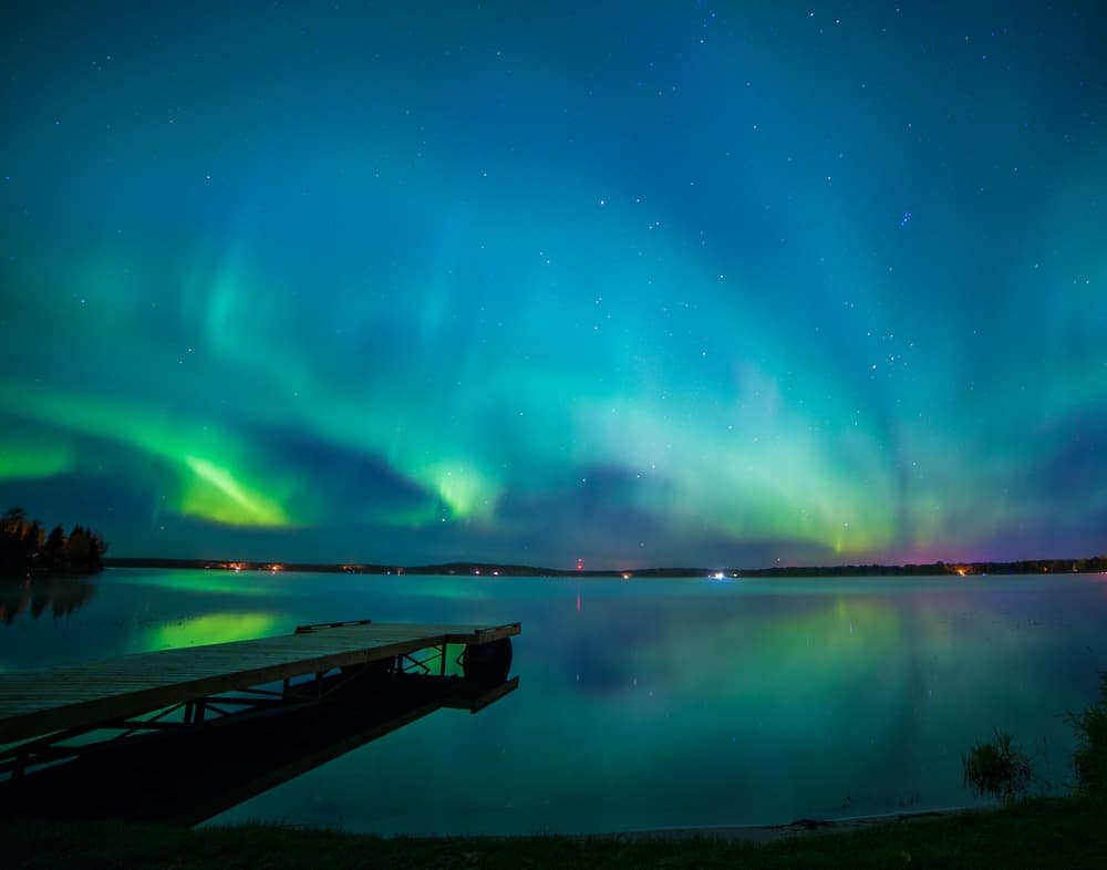 An aurora bore over a lake with a dock in Athabasca County Council.
