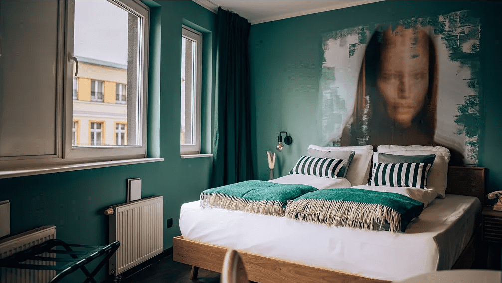 A bed in a room with an experiential painting on the wall, providing a unique hospitality experience in Germany.